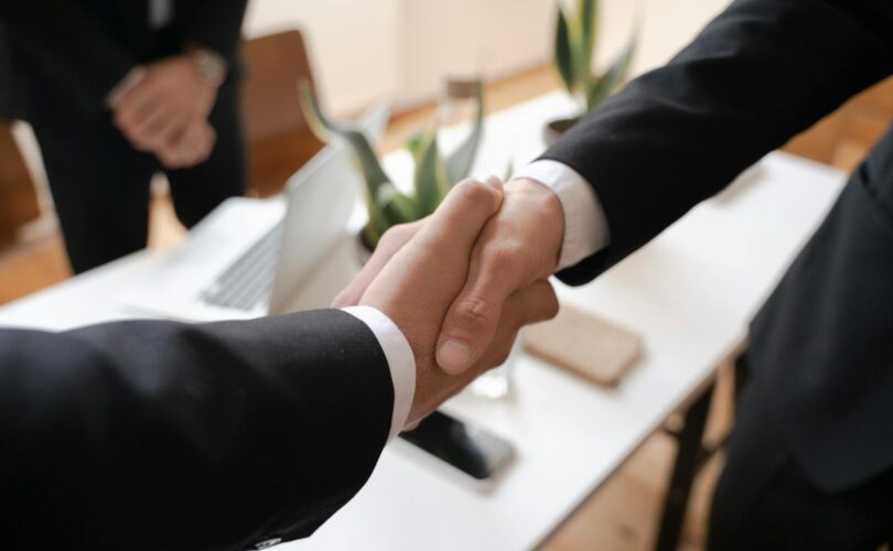 Close-up of a handshake between two professionals in a business setting, symbolizing agreement.